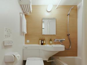 W łazience znajduje się umywalka, toaleta i lustro. w obiekcie R Hotel Kansai Airport w mieście Izumisano