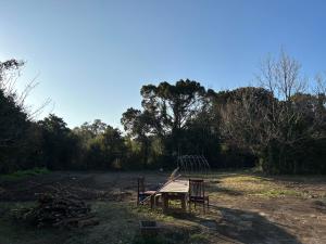 a picnic table and two chairs in a field at ゲストハウス奥屋敷城内 in Kinko