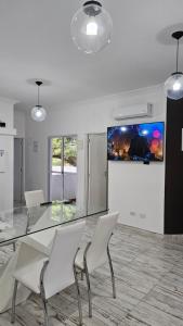 a dining room with a glass table and white chairs at Dpto 4 RaGi in Cordoba