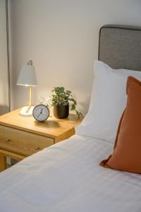 a bed with a nightstand with a clock and a plant at TASTE of African Luxury in the Heart of Brisbane in Brisbane