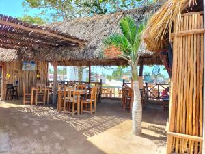 a restaurant with tables and chairs and a straw roof at HOTEL LAS COLORADAS in Yuluc