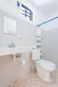 a white bathroom with a toilet and a window at HOTEL LAS COLORADAS in Yuluc
