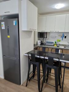eine Küche mit einem schwarzen Tisch und einem Kühlschrank in der Unterkunft Departamento Brisa del sol in Talcahuano