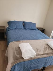 ein Bett mit einer blauen Decke und blauen Kissen in der Unterkunft Departamento Brisa del sol in Talcahuano