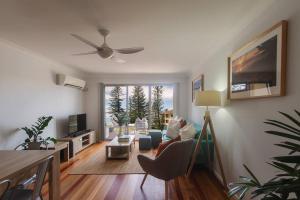 a living room with a couch and a ceiling fan at Bay Properties The Seaspray in Yamba