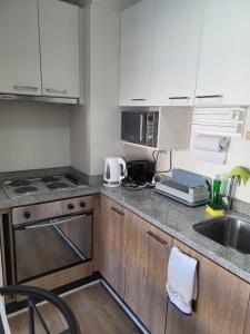 a small kitchen with a sink and a microwave at Departamento Brisa del sol in Talcahuano