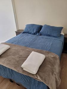 a large bed with blue sheets and blue pillows at Departamento Brisa del sol in Talcahuano