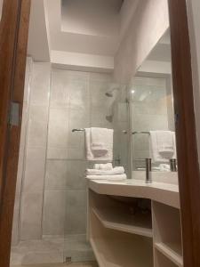 a bathroom with a sink and a shower with towels at Serenity Inn Los Chimus in Tortuga