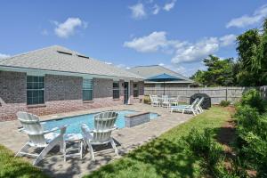 un patio trasero con piscina y sillas y una casa en Salty Seas 405 Sandy Cay en Destin