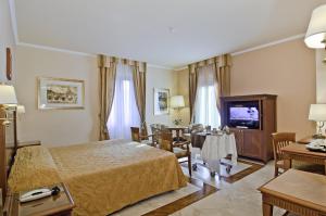 ローマにあるTmark Hotel Vaticanoのベッドとダイニングルームが備わるホテルルームです。