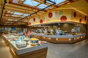 un restaurante con una línea de buffet con personas preparando comida en Senkeien Tsukioka Hotel, en Kaminoyama