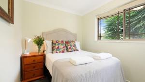 a white bedroom with a bed and a window at Bombo Blue in Kiama