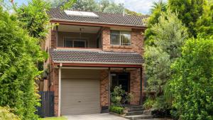 a brick house with a garage and trees at Bombo Blue in Kiama