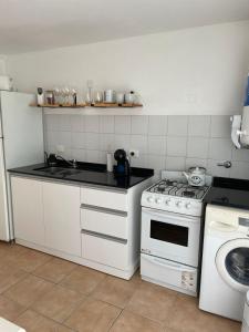 une cuisine blanche avec une cuisinière et un évier dans l'établissement Departamento Emilia 1, à Chascomús