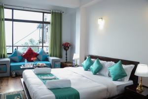 a bedroom with a large bed with blue and green pillows at HOTEL GREENERY VIEW in Gangtok