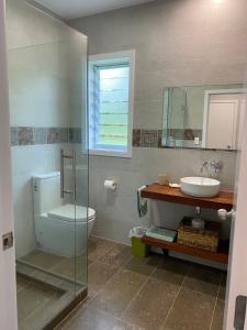 a bathroom with a sink and a toilet and a mirror at Are'ora - the house for living in Rarotonga