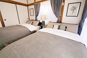2 Betten in einem kleinen Zimmer mit Fenstern in der Unterkunft 梅屋敷貸戸建 in Tokio