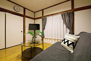 ein Wohnzimmer mit einem Sofa und einem Tisch in der Unterkunft 梅屋敷貸戸建 in Tokio