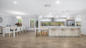 a kitchen with white cabinets and a table and chairs at Paradise in Pearl-walk to beach, ducted air in Pearl Beach