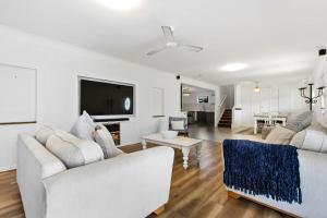 a living room with two white couches and a tv at Unwind on Prince in Urangan