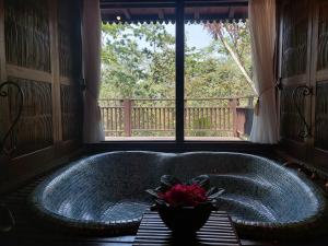 a bath tub with a bowl of flowers in front of a window at MesaStila Resort and Spa in Borobudur