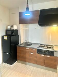 uma cozinha com um frigorífico preto e um lavatório em 東京 足立区青井 Tokyo Adachiku Aoi em Tóquio