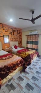 a bedroom with two beds and a ceiling fan at Hong Qi Hotel in Chitwan
