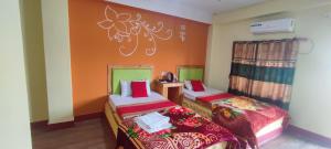 two beds in a room with orange and green at Hong Qi Hotel in Chitwan