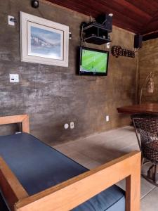 Espaço Verano- quarto Família في نيتيروي: غرفة مع طاولة وتلفزيون على الحائط