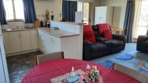 a living room with a kitchen and a table with a red table sidx sidx sidx at Kangaroo Island Accommodation in Kingscote