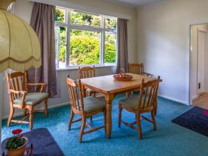 ein Esszimmer mit einem Holztisch und Stühlen in der Unterkunft Kauri Cottage - Marahau Holiday Home in Motueka