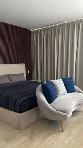 ein Schlafzimmer mit einem Bett, einem Stuhl und Vorhängen in der Unterkunft new charming studio with terrace in Tulum
