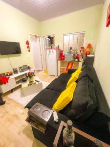 a living room with a black couch with yellow pillows at Kitnet Centro Caraguatatuba in Caraguatatuba