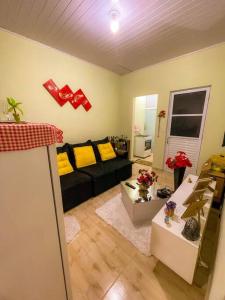 a living room with a black couch and yellow pillows at Kitnet Centro Caraguatatuba in Caraguatatuba