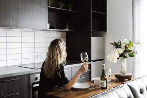 a woman sitting at a table with a glass of wine at Timber Door Luxury Accommodation Geelong in Geelong