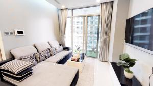 a living room with a couch and a large window at Jessie Saigon Apartment - Vinhome Central Park in Ho Chi Minh City
