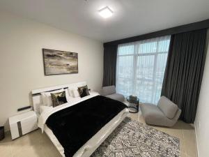 a bedroom with a bed and a chair and a window at CMA Skyline Sanctuary Apartments - Ajman Corniche UAE in Ajman 