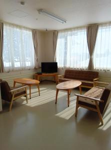 a living room with couches and tables and windows at ゲストハウス ikoi in Kyōgoku