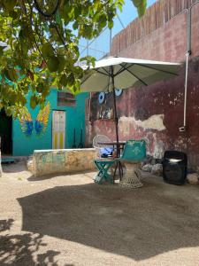 a table with an umbrella and a chair under it at La Casa del Kéej Hostel in Mérida