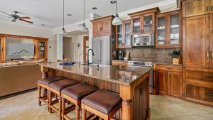 una cocina con armarios de madera y una gran isla con taburetes. en Ground Floor Luxury Penthouse in Poipu Kai, en Koloa