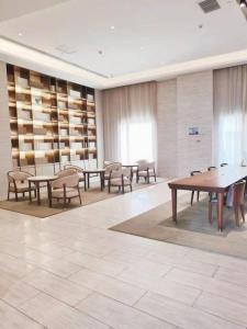une salle avec des tables et des chaises dans une bibliothèque dans l'établissement Ji Hotel Zhangye West Station, à Zhangye