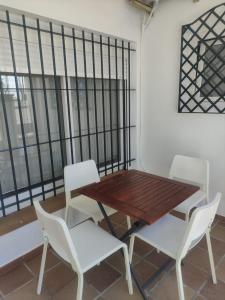 d'une table, de deux chaises blanches ainsi que d'une table et de chaises en bois. dans l'établissement Apartamento en planta baja con vistar al mar, à Conil de la Frontera