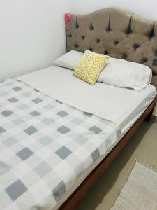 1 cama con colchón a cuadros y 2 almohadas en Mini departamento, en Pucallpa