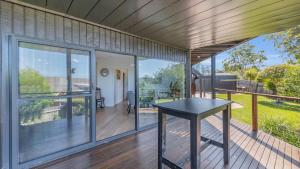 eine offene Veranda mit einem Tisch auf einer Terrasse in der Unterkunft Merimbula Heights 2 in Merimbula