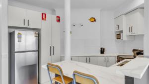 eine Küche mit weißen Schränken sowie einem Tisch und Stühlen in der Unterkunft Merimbula Heights 2 in Merimbula