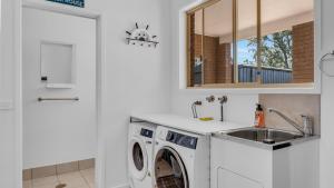 eine Küche mit einer Waschmaschine und einem Waschbecken in der Unterkunft Merimbula Heights 2 in Merimbula