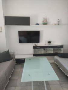 sala de estar con mesa blanca y TV en Apartamento en planta baja con vistar al mar, en Conil de la Frontera