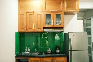 a kitchen with wooden cabinets and a green wall at Central entire house in Hanoi beer street in Hanoi