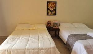 Habitación con 2 camas y mesa con una foto en la pared. en Kame House en Juan Gallego