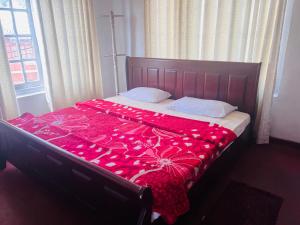 a bed with a red comforter with roses on it at Serendib Hotel in Nuwara Eliya